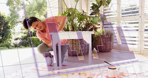 Mature woman painting white side table in sunroom porch, diy furniture makeover with plants