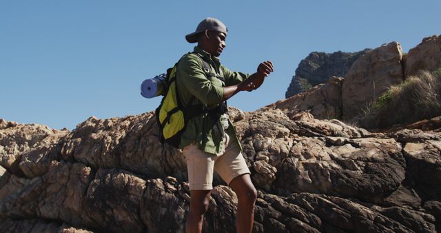African american man hiking in countryside by the coast using his smartwatch. fitness training and healthy outdoor lifestyle.