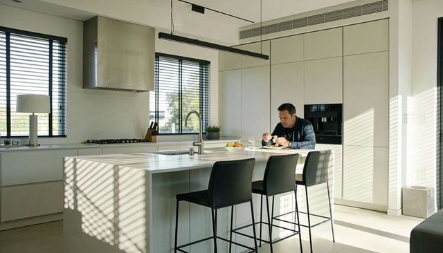 Man eating breakfast at modern minimalist kitchen island with barstools and natural light