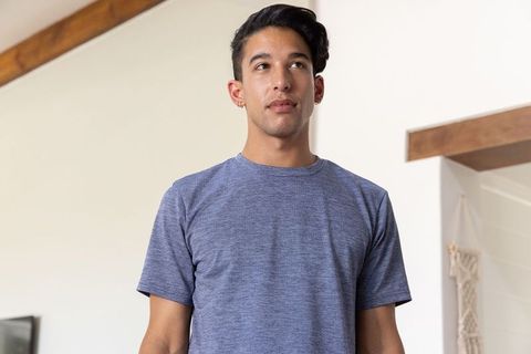 Young african american man standing in modern bright living room wearing blue t-shirt
