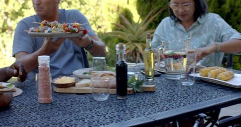 Friends enjoying meal with vegetable skewers and infused water