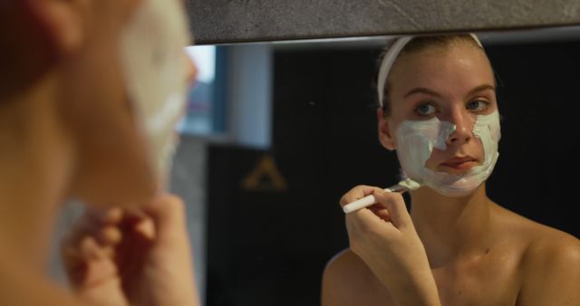 Young Woman Applying Face Mask While Looking in Mirror - Download Free Stock Images Pikwizard.com
