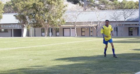 Soccer player training on field near school building