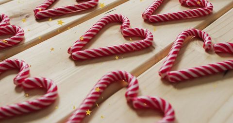 Candy canes shaped as hearts on wooden locale with golden stars