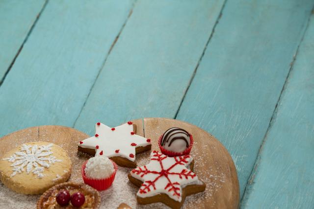This image features beautifully decorated Christmas gingerbread cookies with icing, set on a wooden table. The cookies are star-shaped and adorned with red and white festive decorations, perfect for the holiday season. The table has a rustic wooden texture, adding to the cozy, homemade feel. This image is ideal for holiday-themed advertisements, recipe blogs, and festive greeting cards.