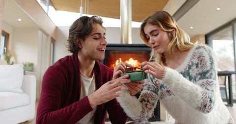 Friends Exchanging Gift by Cozy Fireplace