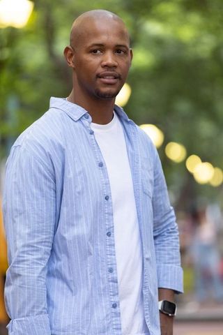 African american man standing in park at dusk wearing smartwatch and blue shirt