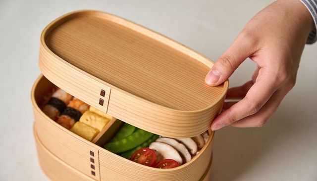 Opening traditional japanese bento box with sushi, tamagoyaki and fresh veggies