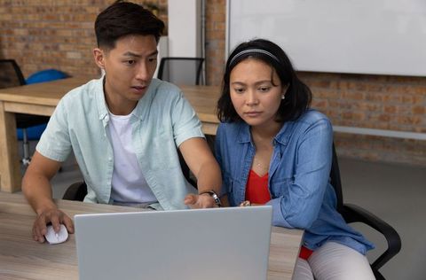 Asian Coworkers Collaborating on Laptop in Meeting Room