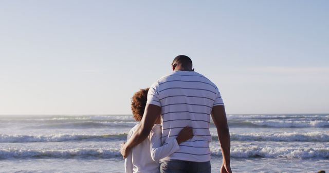 This image depicts a couple embracing while standing on the beach, facing the ocean during sunset. The peaceful setting makes it ideal for use in romantic travel brochures, relationship blogs, or inspirational social media posts emphasizing love and togetherness.