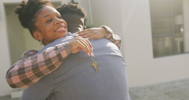 This image captures the joyful moment of a couple embracing as they celebrate moving into their new home, with one of them holding a key. It is perfect for use in real estate promotions, home ownership magazine articles, advertisements for moving services, or websites focused on home and family dynamics.