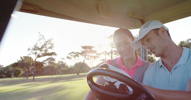 Golfers sitting in golf buggy using mobile phone at golf course