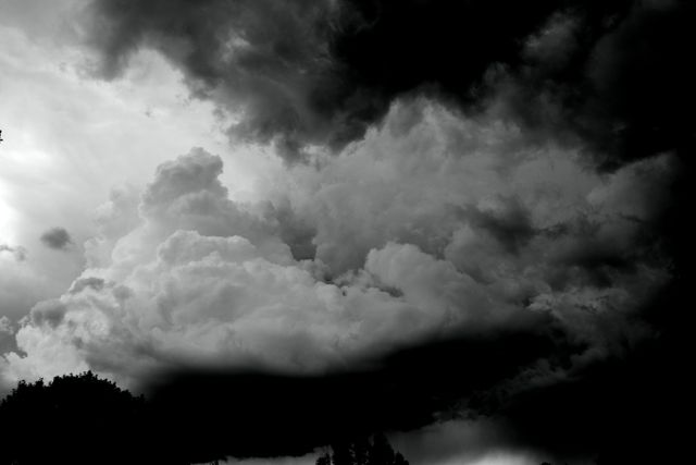 Dramatic black and white storm clouds filling the sky, creating a moody and ominous atmosphere. Useful for backgrounds in weather forecasts, dramatic storytelling settings, environmental projects, and artistic presentations.