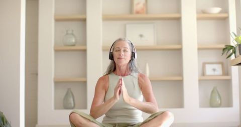 Mature Woman Meditating with Headphones at Home