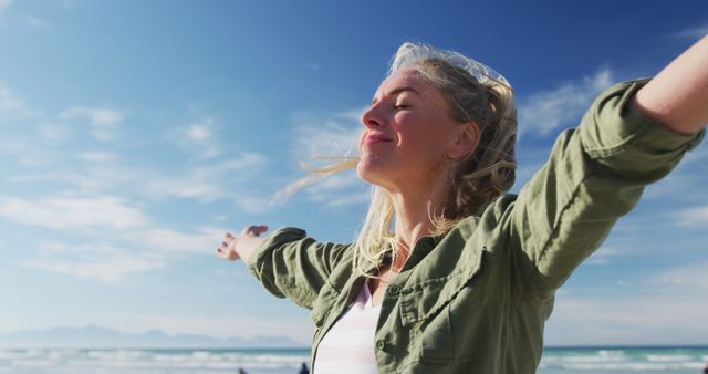 Caucasian woman with arms wide, smiling at the beach on sunny day - Download Free Stock Photos Pikwizard.com