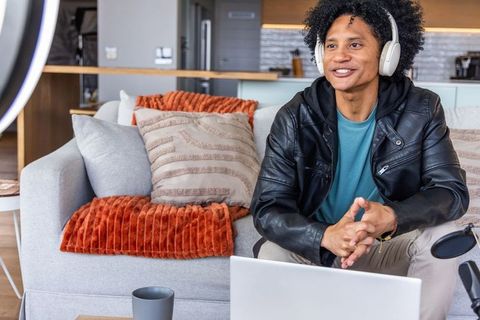 African american vlogger recording podcast and live streaming on laptop with headphones