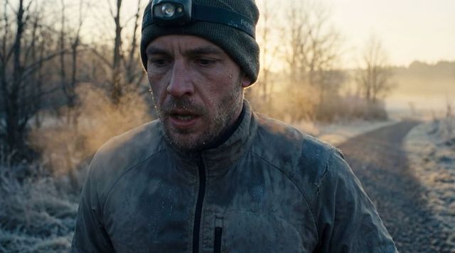 Dawn hiker breathing visible vapor wearing knit beanie and headlamp hiking frosty trail