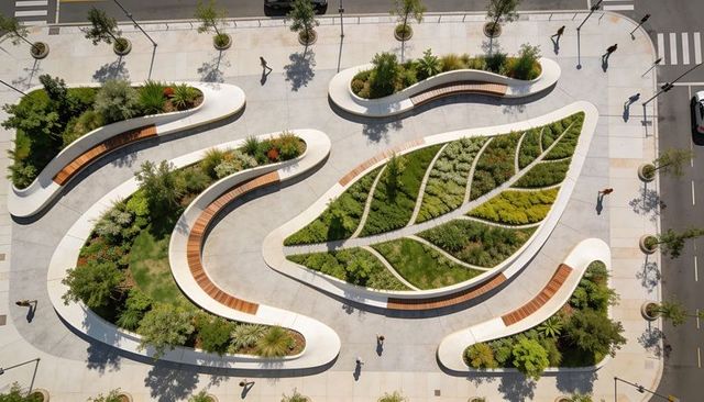 Aerial urban plaza featuring leaf-shaped planted bed and sculptural white curved benches