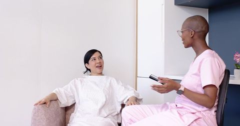 Patient sitting and talking with clinician holding tablet during clinic consultation