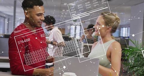 Young Professionals Collaborating with Augmented Data Overlays on Laptop in Open Office