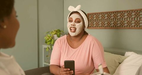 Woman Chatting While Wearing Facial Mask and Bow Headband on Cozy Living Room Sofa