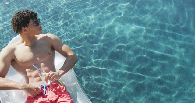 Young Man Relaxing on Pool Float with Refreshing Drink - Download Free Stock Images Pikwizard.com