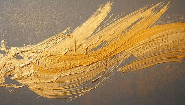 Sweeping metallic gold impasto brushstroke across gray canvas abstract texture