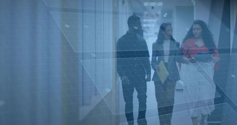 Diverse team walking and discussing projects in modern office corridor with glass grid