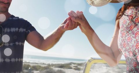 Couple Holding Hands with Sun Flares at Beach