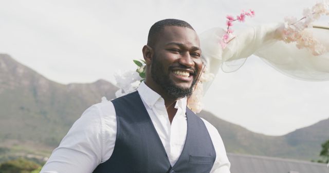 Image of happy african american groom smiling and walking at outdoor wedding. Marriage, love, happiness and inclusivity concept.