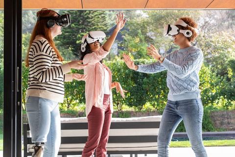 Diverse women enjoying vr experience outdoors on patio