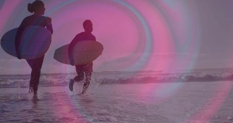 Surfers holding boards in sunset glow