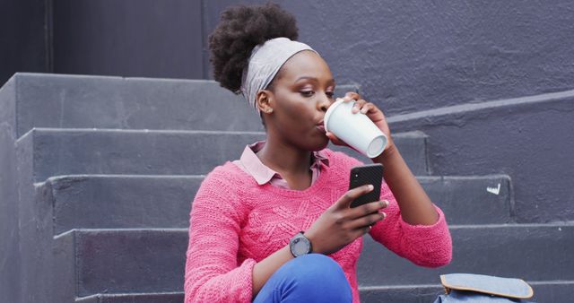 Young African American Woman Drinking Coffee While Using Smartphone on Outdoor Steps - Download Free Stock Images Pikwizard.com