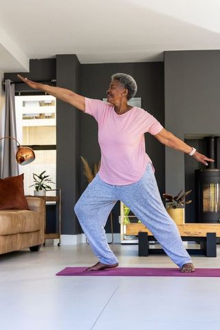 Senior african american woman practicing standing yoga in modern living room for balance