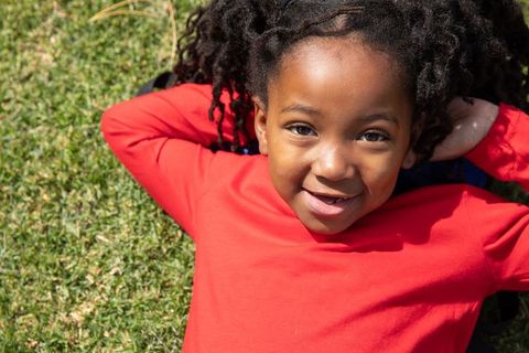 Happy African American Child Relaxing on Lawn