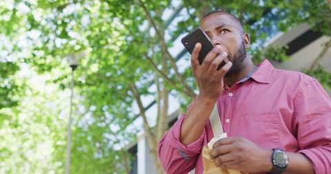 Man Using Smartphone and Eating in Urban Environment