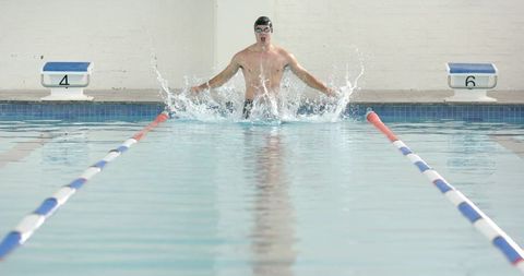 Male swimmer training in competition pool lane with splash