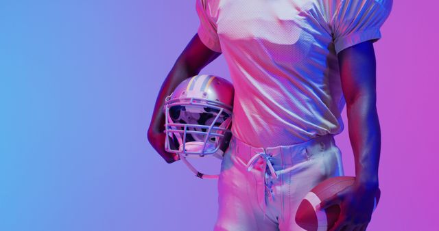 Image of portrait of african american american football player over blue to pink neon background. American football, sports and competition concept.