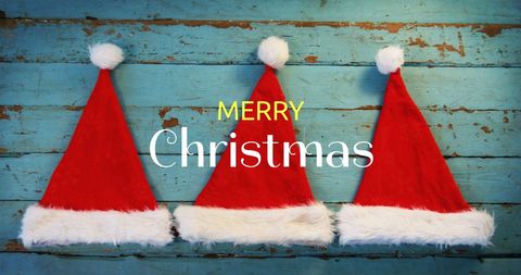 Merry Christmas Greeting with Santa Hats on Rustic Wood