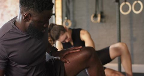 Diverse workout partners stretching in modern gym environment