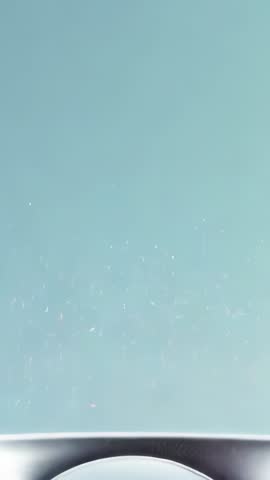 Futuristic vertical video of reflective clock sphere panning to droplet emerging in teal sky