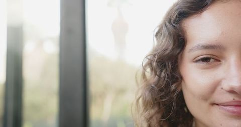 Woman Smiling on Balcony with Natural Light and Blurred Greenery