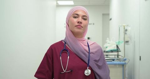 Confident muslim nurse wearing hijab and stethoscope in hospital corridor