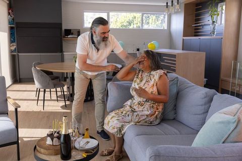 Senior couple laughing and celebrating at home with cake and champagne