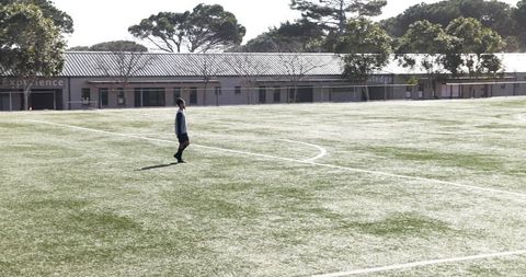 Youth Soccer Player on Empty Field Under Sunlit Sky