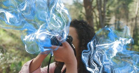 Woman photographer shooting with dslr in forest with cinematic blue abstract overlays