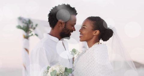 Bride and Groom Embracing on Beach Amid Light Spots