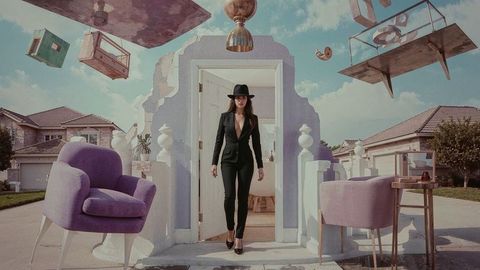 Surreal woman in black suit walking through artistic floating doorway