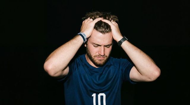 Stressed soccer player gripping head and raking hair in frustration and intensity