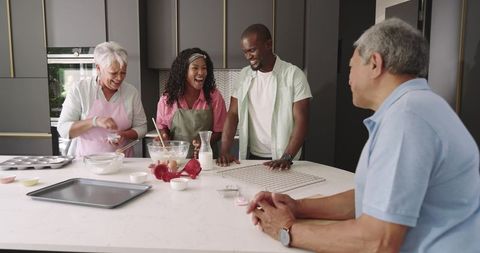 Multigenerational family baking on modern kitchen island, laughing while mixing batter